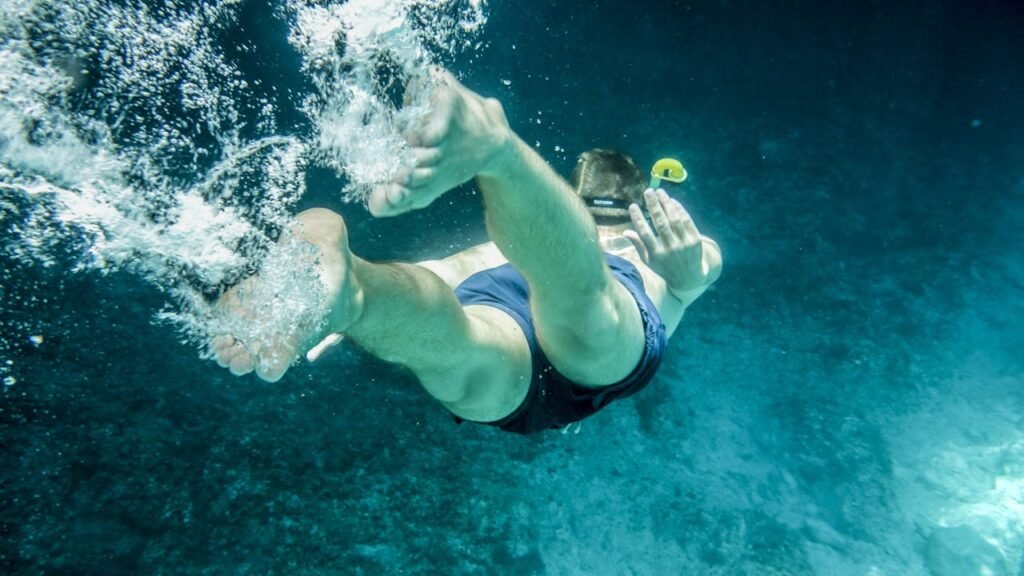 A man snorkeling underwater exploring the clear blue tropical sea. Adventure and recreation captured in action.